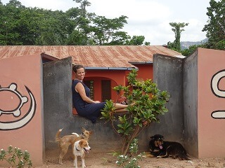 Patricia zit op een muur voor haar huis met haar honden